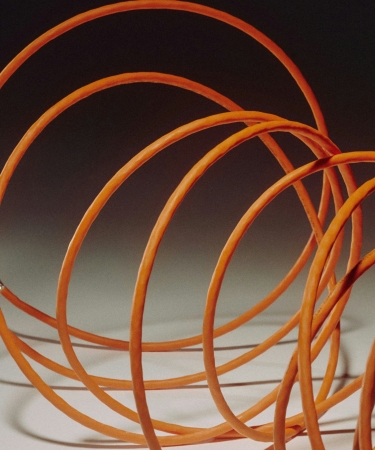 An abstract, colorful image featuring swirling lights in shades of orange, purple, and yellow, against a mostly black background