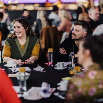 Group of people smiling and chatting around a table during a workshop or roundtable session.