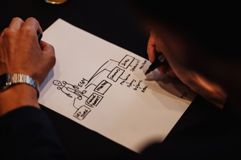 An attendee sketching an organisational chart during a session at Design Leadership 2025 in Melbourne, using a black marker on a worksheet.