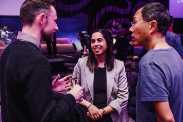 Brendan Jarvis, Vinita Israni, and Ming Lee share an engaging conversation at the DesignOutlook 2024 VIP Cocktail Party in a lively, purple-lit space.
