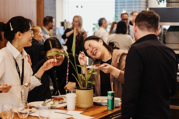 Attendees at Design Leadership 2025 share a lively, laughter-filled moment over lunch, gathered around a table in a buzzing, informal setting.