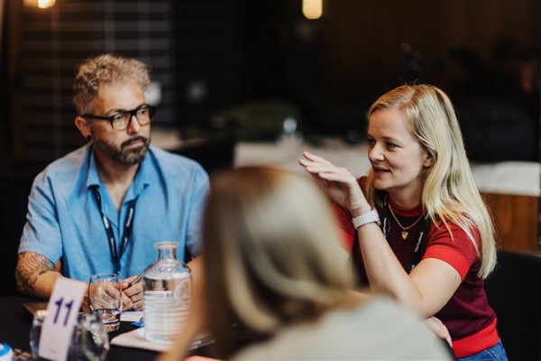 Attendees at table 11 engage in a focused conversation during a breakout session at Design Leadership 2025, exchanging insights and ideas.