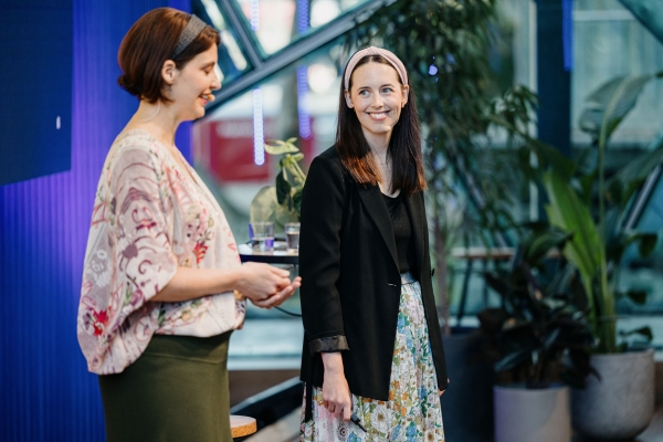 Nicole Austin and Louise Sporton present at Design Outlook 2022. Nicole wears a floral blouse and green skirt; Louise wears a floral skirt and black blazer.