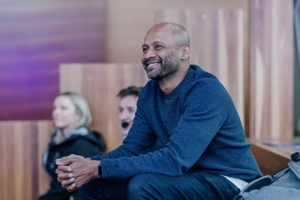 Mathan Ratnam, a presenter at Design Outlook 2022, smiling while seated in the audience during a session. He’s wearing a navy sweater and appears engaged and relaxed.