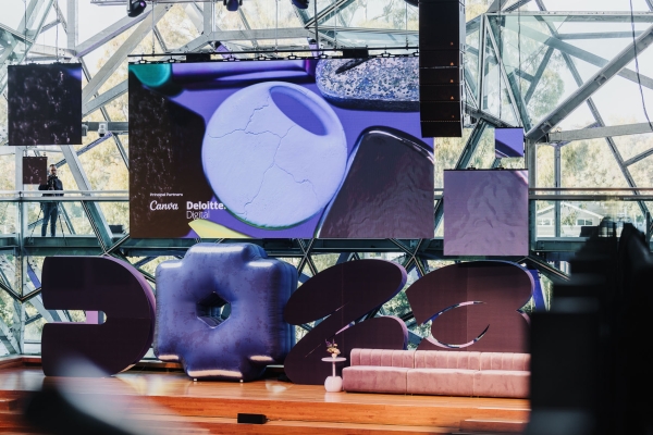 Design Outlook 2023 stage with bold sculptural “2023” set pieces, velvet couch, and a large digital screen featuring Canva and Deloitte Digital.