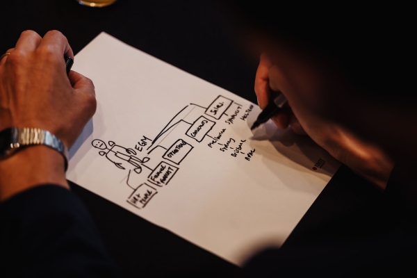 An attendee sketching an organisational chart during a session at Design Leadership 2025 in Melbourne, using a black marker on a worksheet.
