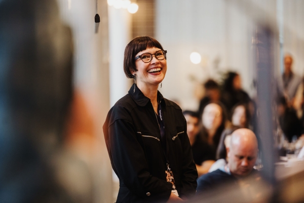 Presenter Angela Bliss smiling during a session at Design Leadership 2025 in Melbourne, with attendees seated in the background.