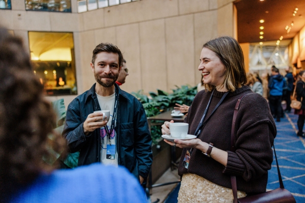 Two attendees enjoy coffee and conversation during a break at The Outlook, smiling and relaxed in the venue’s open-air atrium.