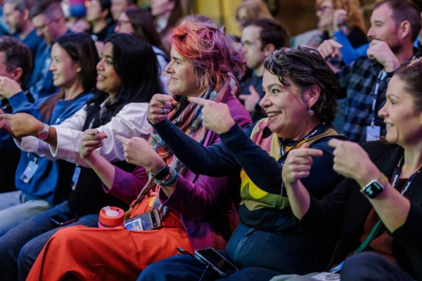 Audience members at The Outlook smile and engage in a lively interactive session, pointing and laughing together during a fun activity.
