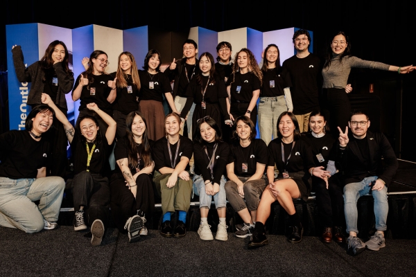 Group photo of smiling Accessibility & Inclusion 2025 volunteers, posing together on stage after a successful event.