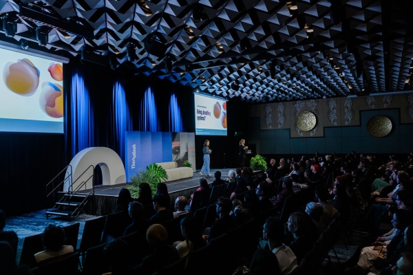 Laura Kostanski presenting on stage at Design Outlook 2025, Sofitel Melbourne, with slides on design disciplines and a packed seated audience.